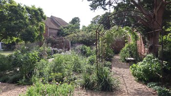 In this Georgian walled garden I created a classic quartered arrangement of reclaimed Yorkstone paths with exuberant mixed planting of roses and herbaceous perennials and an elegant metal pergola around the edges.