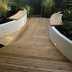 Coastal inspired small garden with cedar decking and raised beds incorporating seating