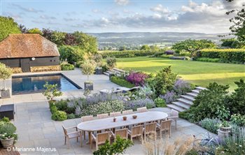 Cosy outdoor spaces contained within romantically planted banks in a Sussex country garden with views to the South Downs