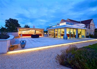 Night time picture of an outdoor kitchen and seating area with roof terrace and hot tub